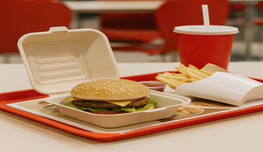 Fast food meal with a burger, fries, and soda served in an eco-friendly bamboo fiber takeout container