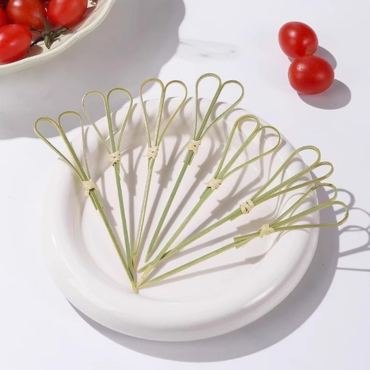 Mini bamboo knot skewers arranged neatly on a white plate, ideal for serving cherry tomatoes and appetizers.