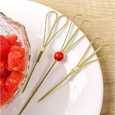 Mini bamboo knot skewers with loop design used to serve cherry tomatoes and watermelon on a white plate.
