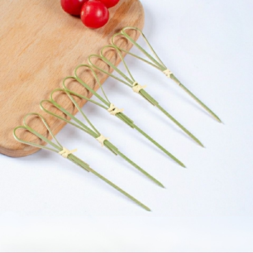 Mini bamboo skewers with decorative loop tops displayed on a wooden board, ideal for appetizers and garnishes.