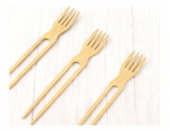 Three bamboo chop-forks arranged on white wooden background
