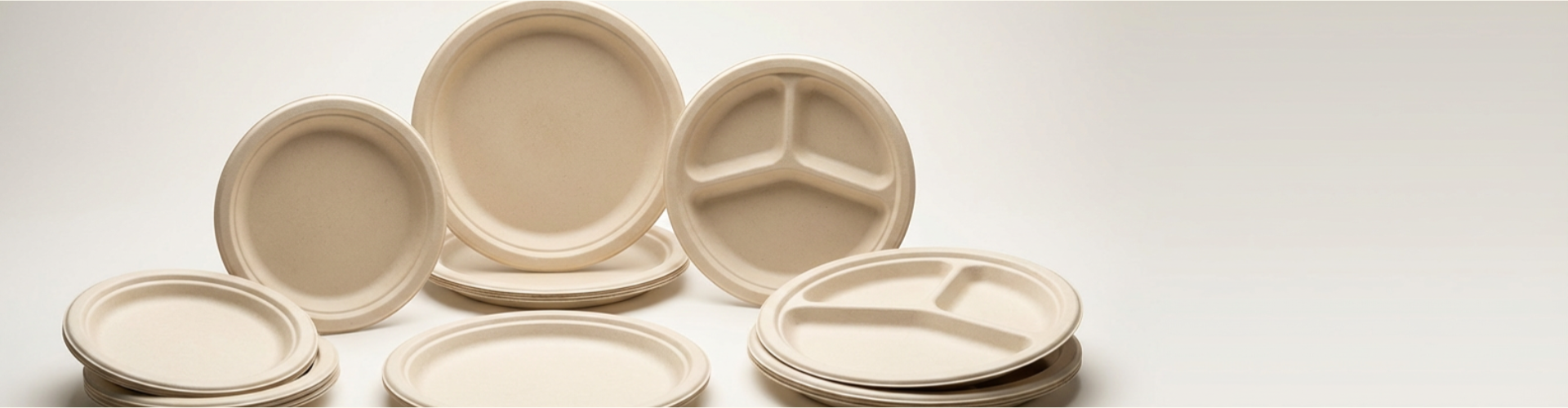 Stacked bamboo fiber plates in bulk, including round and compartment plates for wholesale supply.